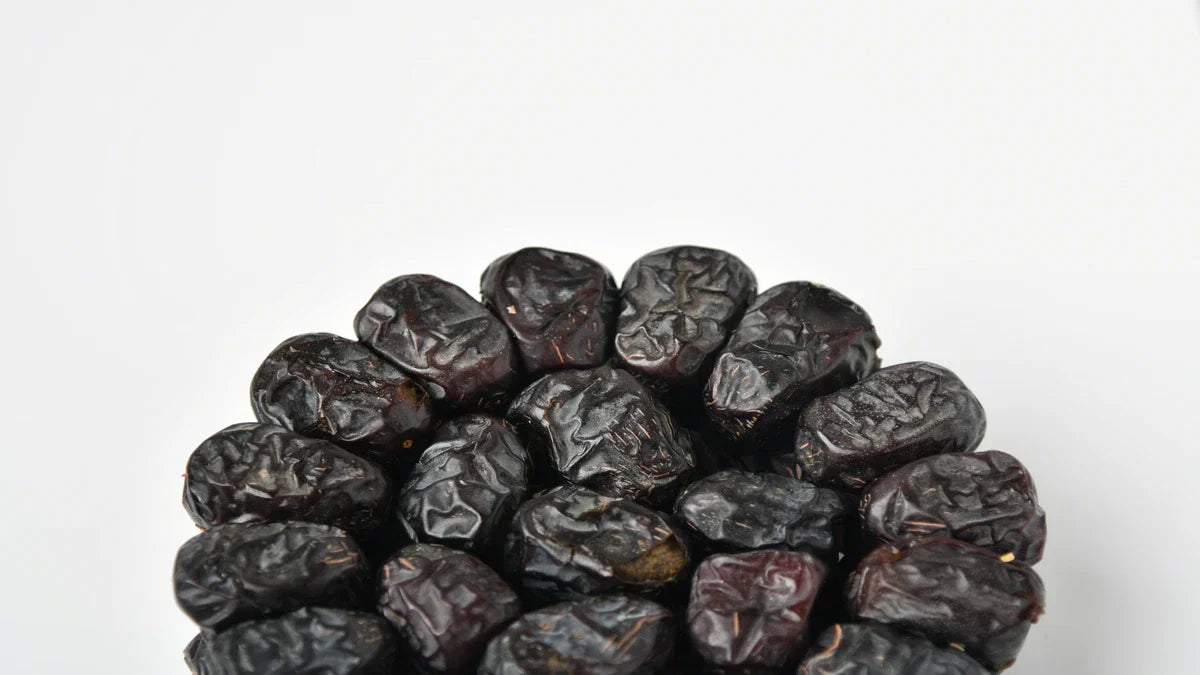 A clustered arrangement of dark, textured Ajwa premium dates against a clean white background.