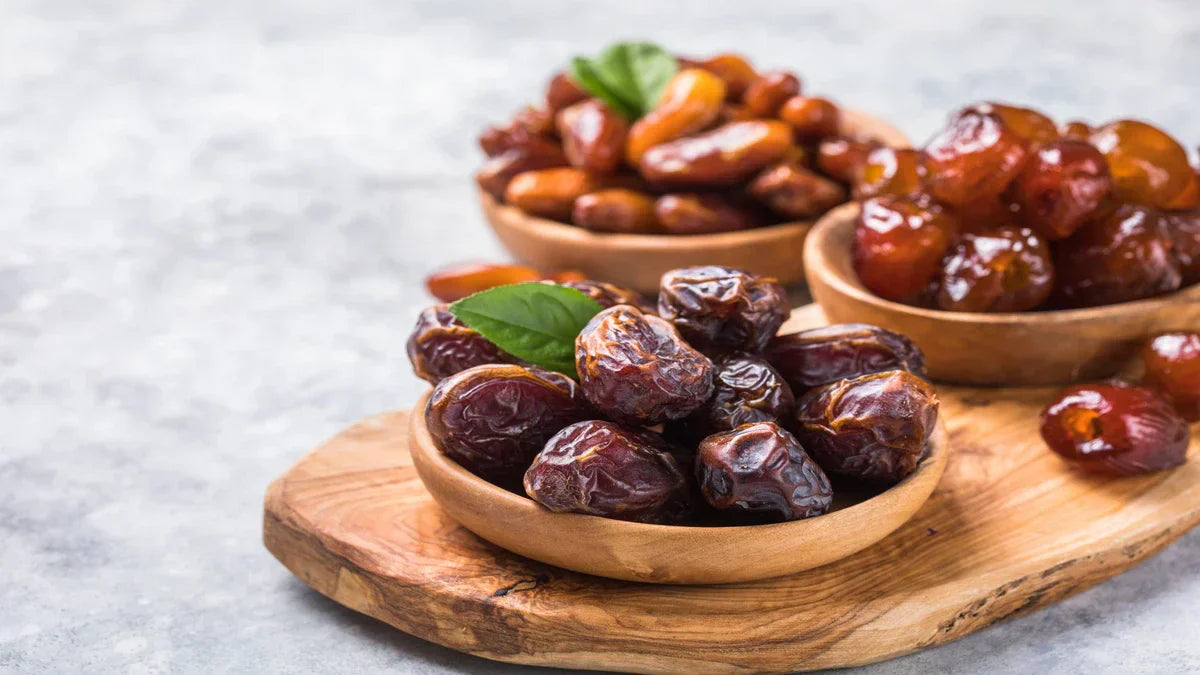 Bowls of assorted kurma dates arranged on a wooden platter, ideal for healthy Raya corporate gifts malaysia.