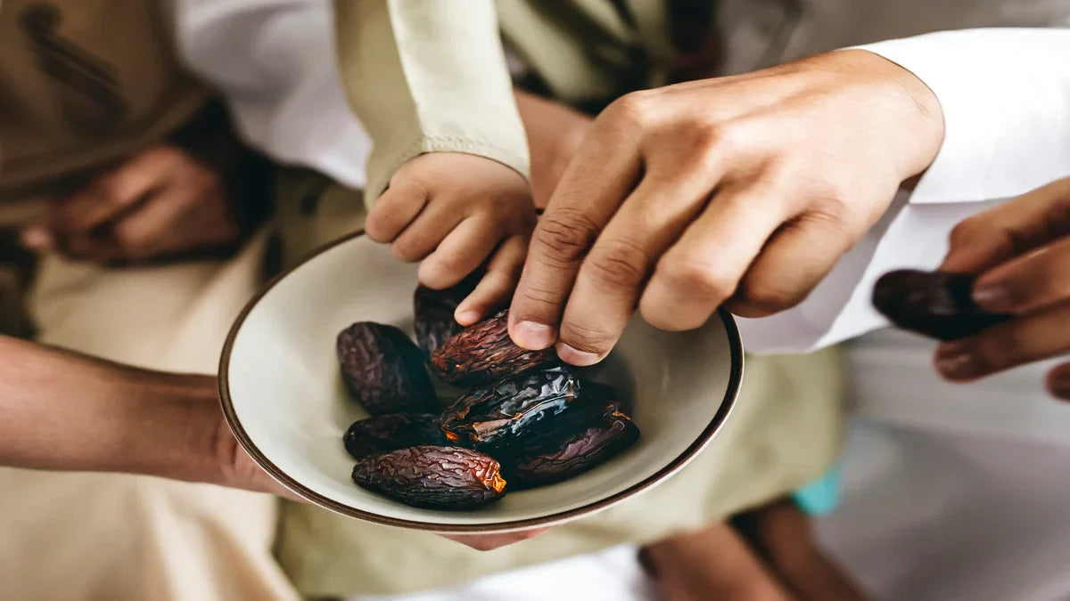 Hands of different generations reaching into a bowl to share premium dates, a perfect choice for natural halal snacks.